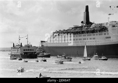 QE2 kehrt nach Southampton zurück. Union Jacks sind auf Autos festooniert, auf Schultern drapiert, auf Stöcken gewellt. Southampton begrüßt den Luxusliner aus dem Jahr QE2, der zum Trooper wurde und aus dem Krieg zurückkehrt, mit einem „Three Cheers“. An Bord ist ihre kostbare Fracht, die 700 Überlebenden der HMS Coventry, Ardent und Antelope, im Kampf um die Falklands versunken. 11.. Juni 1982. Stockfoto