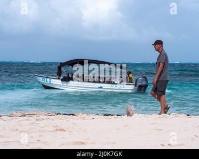 Playa de Spratt Bight, San Andrés, Kolumbien - November 17 2021: Viele Touristen nehmen ein Motorboot, um das Fisch- und Meeresleben zu sehen, während ein Mann zu Fuß geht Stockfoto