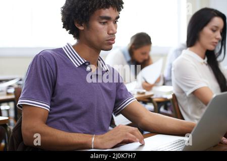 Eingetaucht in sein Projekt. Aufnahme einer Gruppe von Studenten, die im Unterricht an Laptops arbeiten. Stockfoto