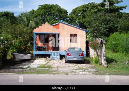 San Andrés, San Andrés y Providencia, Kolumbien - November 18 2021: Kleines Haus in weichem Orange mit einem Auto, das auf dem Hof in der Nähe eines Bootes geparkt ist Stockfoto