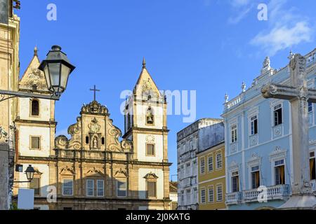 Fassade einer alten historischen Kirche und farbenfrohe Häuser im Kolonialstil auf dem zentralen Platz des Pelourinhous Stockfoto