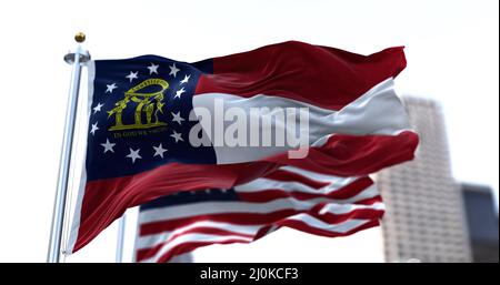 Die Flagge des US-Bundesstaates Georgia winkt im Wind, die Flagge der amerikanischen Sterne und Streifen verschwimmt im Hintergrund Stockfoto