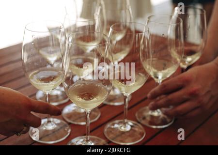 Gläser mit verschiedenen Weinsorten und menschlichen Händen, die Weingläser im Hintergrund halten Stockfoto