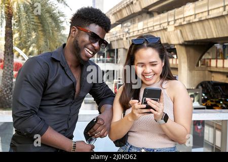 Porträt zweier multiethnischer Freunde, die das Handy in einem Einkaufszentrum benutzen Stockfoto