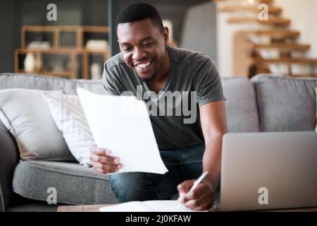 Verwalten einer Menge Aufgaben von zu Hause aus. Aufnahme eines jungen Mannes, der zu Hause Papierkram durchläuft. Stockfoto