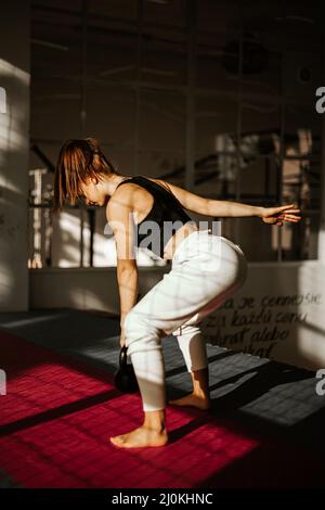 Frau tut Kettlebell schwingen. Mädchen im Rücken, die Krafttraining übt Stockfoto