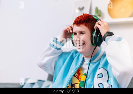 Moderne junge Frau, die ihre Helme auf dem Sofa im Wohnzimmer auszieht Stockfoto