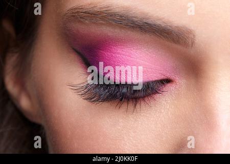 Nahaufnahme eines geschlossenen menschlichen weiblichen Auges. Mädchen mit perfekter Haut und rosa Augen Schatten Stockfoto