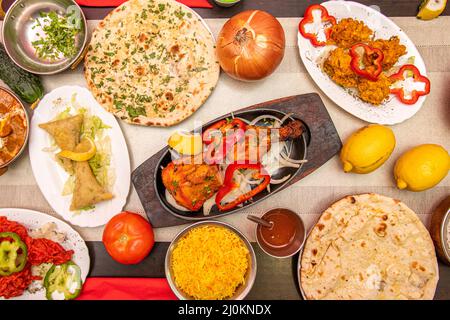 Set von indischen Gerichten mit Händen Tauchen Sie das Huhn Tikka Masala, ein weiteres in die gefüllten Samosas und das Pfeffer-und Knoblauch Naan und Saucen Stockfoto