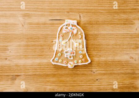 Glockenförmiger Lebkuchen, verziert mit Glasur und Streusel, auf einem hellen Holz-Textur Hintergrund. Stockfoto