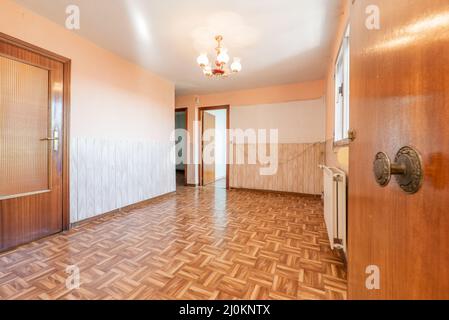 Hauseingang mit Holztür zum leeren Wohnzimmer mit ähnlichen Holzboden und Vintage-Dekor Stockfoto