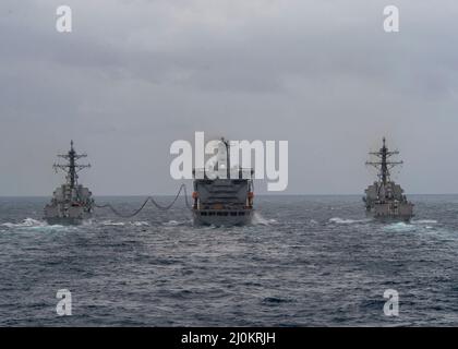 220224-N-EH998-1020 OZEAN (FEB 24,2022) die Geschoßjägerzerstörer USS Bulkeley (DDG 89), links, und die USS Delbert D. Black (DDG 119) rechts, Transit neben USNS John Lenthall (T-AO 189) während einer Auffüllung auf See während des Surface Warfare Advanced Tactical Training (SWATT). Bulkeley und Delbert D Black sind Teil von Destroyer Squadron (DESRON) 26, das die Carrier Strike Group (CSG) 10 unterstützt. SWATT wird vom Naval Surface and Mine Warfighting Development Center (SMWDC) geleitet und soll die Kampffähigkeit, Letalität und Interoperabilität der teilnehmenden Einheit verbessern Stockfoto