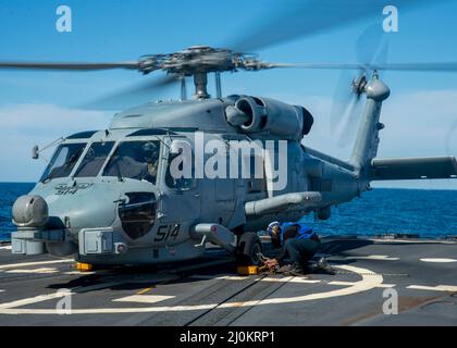 220301-N-EH998-1026 ATLANTISCHER OZEAN (MÄRZ 1,2022) David Wright, die Mate 3.-Klasse von Boatswain, sichert sich einen MH-60 Sea Hawk-Hubschrauber, der dem Hubschrauber Maritime Strike Squadron (HSM) 26 zugewiesen wurde, an Bord des Lenkraketen-Zerstörers USS Farragut (DDG 99), während er für Surface Warfare Advanced Tactical Training (SWATT) unterwegs ist. Farragut ist Teil von Destroyer Squadron (DESRON) 26, das die Carrier Strike Group (CSG) 10 unterstützt. SWATT wird vom Naval Surface and Mine Warfighting Development Center (SMWDC) geleitet und soll die Kampffähigkeit, Letalität und Interoperabilität der teilnehmenden Einheiten verbessern. Stockfoto