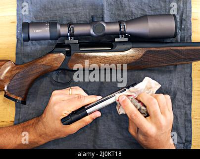 Regelmäßige Wartung ist für jeden Waffenbesitzer unerlässlich. Beschnittene Ansicht eines Mannes, der sein Gewehr putzt. Stockfoto
