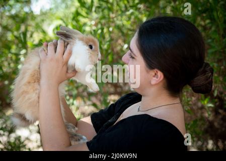 Junge schöne Frau mit einem schwarzen Kaninchen Haustier Tier. Häusliche Tierpflege Stockfoto