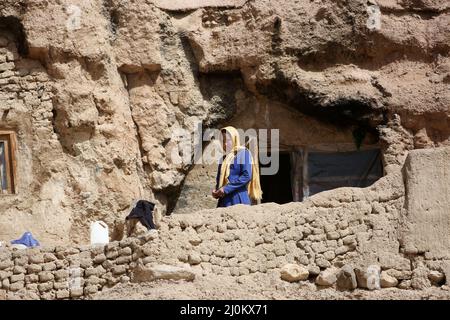 Bamiyan, Afghanistan. 19. März 2022. Ein afghanisches Mädchen steht in der Nähe der Höhle, in der sie in der Provinz Bamiyan, Afghanistan, lebt, 19. März 2022. Quelle: Saifurahman Safi/Xinhua/Alamy Live News Stockfoto