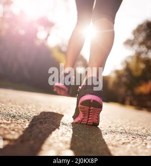 Auf lange Sicht in der IT. Kurze Aufnahme einer Frau, die sich für einen Lauf die Beine ausstreckt. Stockfoto