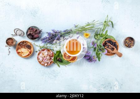 Bio-Tee. Kräuter, Blumen und Früchte um eine Tasse Tee, ein flaches Lay, Top Shot Stockfoto