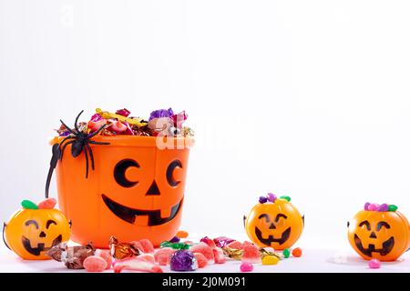 Zusammensetzung von halloween Eimer mit Trick or Treat Süßigkeiten, Spinne und Kürbisse auf weißem Hintergrund Stockfoto