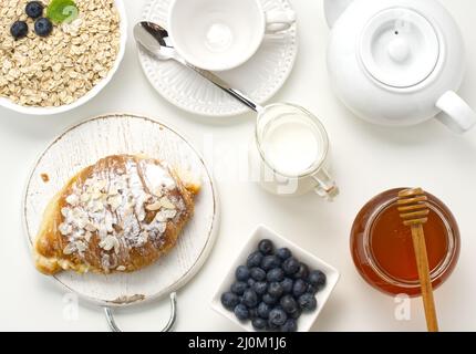 Roher Haferflocken in weißer Keramikplatte, Heidelbeere, Honig auf weißem Tisch, Frühstück Stockfoto