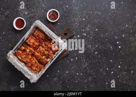 Geröstete Schweinefleischrippen in Folie in Metallbackform. Amerikanisches Speisekonzept. Draufsicht, Kopierbereich Stockfoto