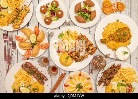 Persische Gerichte mit Holzkohle gegrilltem Huhn, Patties, gegrilltem Huhn und Kofta Spieße, Hummus mit Olivenöl und Paprika, geschmortes Huhn, oran Stockfoto