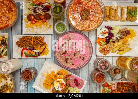 Bunte Teller mit Speisen aus dem Nahen Osten mit verschiedenen Arten von Hummus, Vorspeisen, Basmati-Reis, Falafel, Pilau-Reis, Baklava und viele verschiedene Gewürze Stockfoto