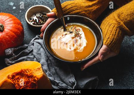 Weibliche Hände mit Schale Kürbissuppe Stockfoto