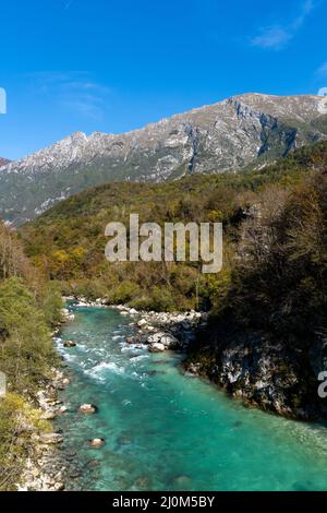 Eine wunderschöne herbstliche Farblandschaft in den Julischen Alpen Sloweniens mit dem klaren türkisfarbenen Fluss Soca im Vordergrund Stockfoto