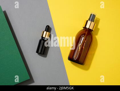 Braune Glasflaschen mit Pipette auf gelbem Hintergrund. Kosmetik SPA Branding Mockup, Draufsicht Stockfoto