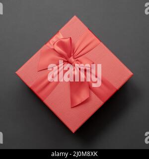 Rote Box mit Schleife auf dunkelgrauem Hintergrund. Draufsicht. Stockfoto