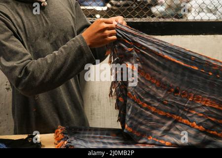 MN Hands faltete die Stoffe in der Schneiderwerkstatt. Gefaltetes quadratische Muster, Sarong Stockfoto