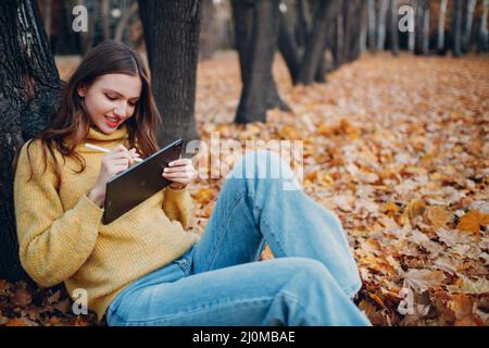 MOSKAU, RUSSLAND - 19. OKTOBER 2021: Junge Frau Modell sitzen mit Tablet Apple iPad Pro 2021 und malen mit Stift in Stockfoto