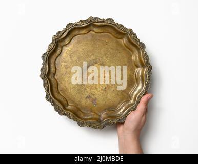 Weibliche Hand hält leere Kupfer runde vintage Teller auf weißem Hintergrund, Obstschale Stockfoto