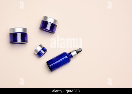 Blaue Glasflaschen mit Pipette und Glas auf beigem Hintergrund. Kosmetik SPA Branding Mockup Stockfoto