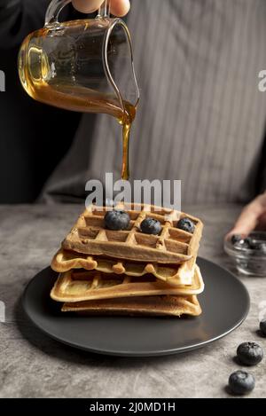 High-Angle-Mann Gießen Sirup Stapel Waffeln Stockfoto