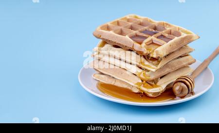 Platte mit hoch angewinkelten, honigbedeckten, gestapelten Waffeln und Platz zum Kopieren Stockfoto