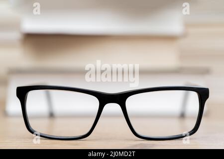 Gläser auf dem Hintergrund der Bücher. Symbol von Wissen, Wissenschaft, Studium, Weisheit. Stockfoto