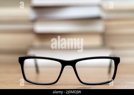 Gläser auf dem Hintergrund der Bücher. Symbol von Wissen, Wissenschaft, Studium, Weisheit. Stockfoto