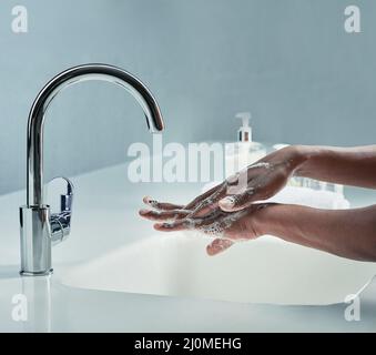Reinigen Sie es so, als ob Sie es meinen. Ein kurzer Schuss eines Mannes, der sich die Hände in einem Waschbecken im Badezimmer wascht. Stockfoto