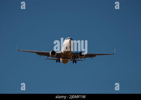 Passagierflugzeuge mit zwei Düsenflugzeugen, die am blauen Himmel an Land kommen Stockfoto