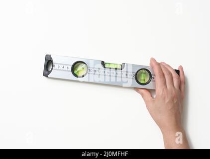 Weibliche Hände halten eine graue metallische Gebäudeebene auf weißem Hintergrund. Messgerät Stockfoto