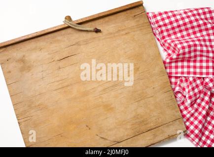 Leere rechteckige Holzküche Schneidebrett und rotes Handtuch in einem weißen Käfig auf einem weißen Tisch, Draufsicht Stockfoto