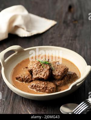 Lapis Daging, süßer Rindergulasch aus Ost-Java. Aus gekochtem Rindfleisch mit Sojasoße. Auf Holztisch Stockfoto