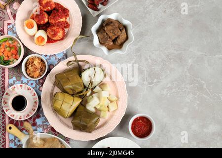 Ketupat Lebaran. Traditionelles festliches Gericht aus Reiskuchen oder Ketupat mit verschiedenen Beilagen, beliebt während der Eid-Feierlichkeiten. Speicherplatz kopieren für Stockfoto