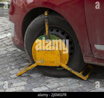 Ein Vorderrad, das durch Radsperre blockiert ist, um nicht autorisierte oder illegale Parkplätze zu erhalten. Eine Radklemme, die auch als Radmanschette oder Parkmöglichkeit bezeichnet wird Stockfoto