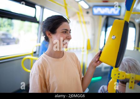 Frau Zahlung conctactless mit Smartphone für die öffentlichen Verkehrsmittel in der Straßenbahn Stockfoto