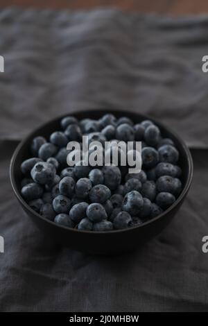 Große Schüssel mit Heidelbeeren auf dem Tisch, flacher Fokus Stockfoto