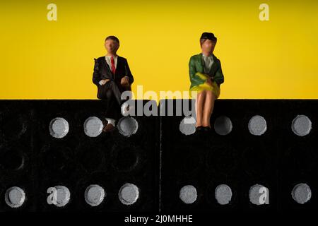 Geschäftsmann und -Frau sitzen auf Domino-Token Gelber Hintergrund Stockfoto