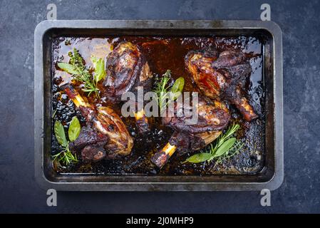 Traditionelle geschmorte langsam gekochte Lammschenkel in Rotweinsauce mit Kräutern serviert als Draufsicht in einem Barbecue-Blech Stockfoto